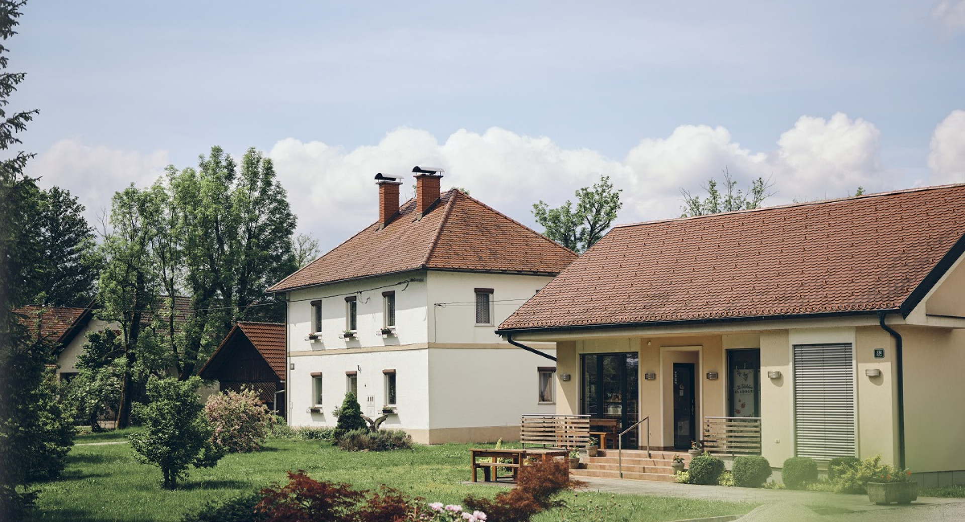 Velika bela in manjsa oranzna hisa na jasi, obdani z zelenjem.