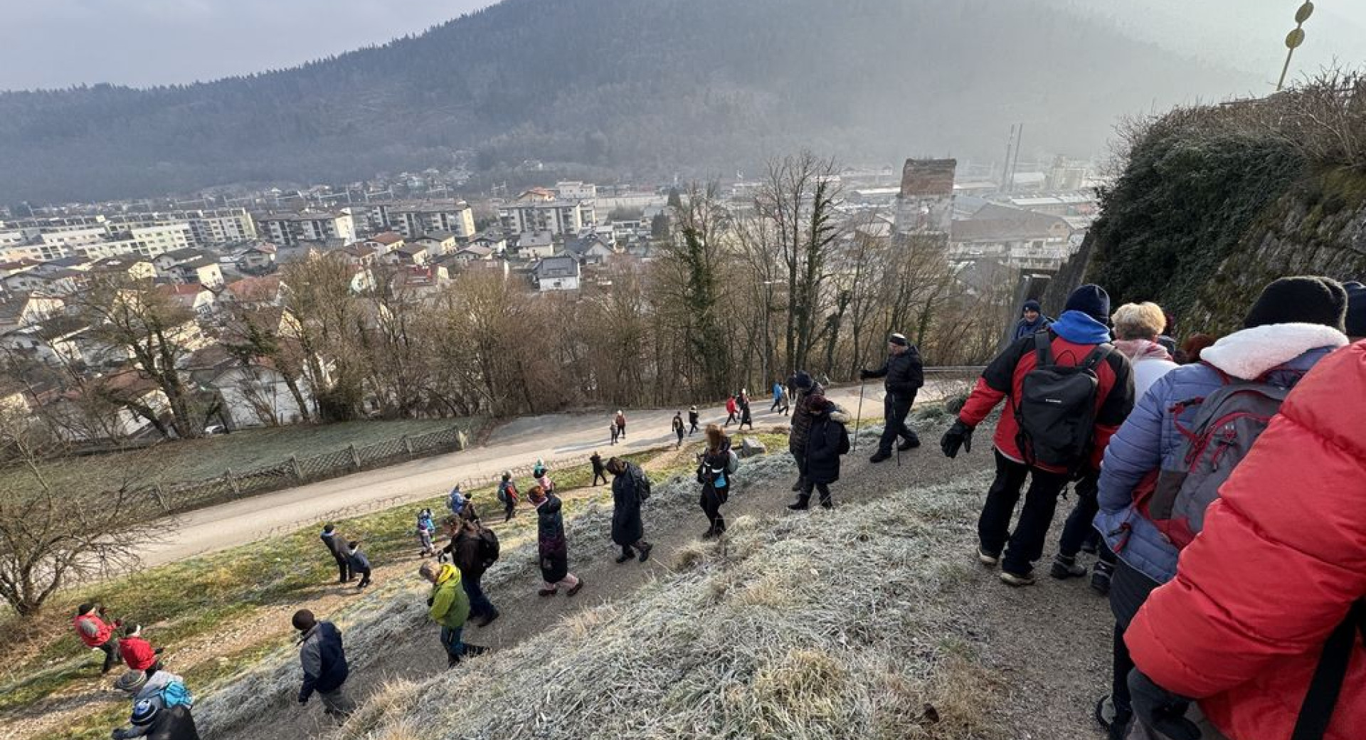 Pohodniki se spuščajo po travnatem pobočju.