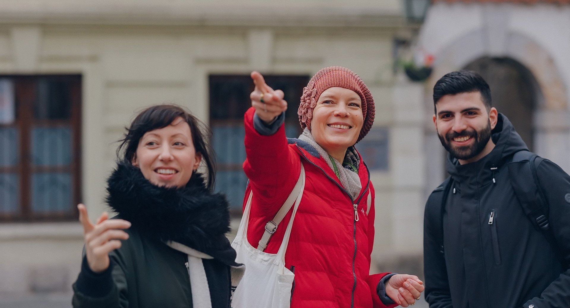 Dekle v rdeči bundi razlaga fantu in dekletu. 