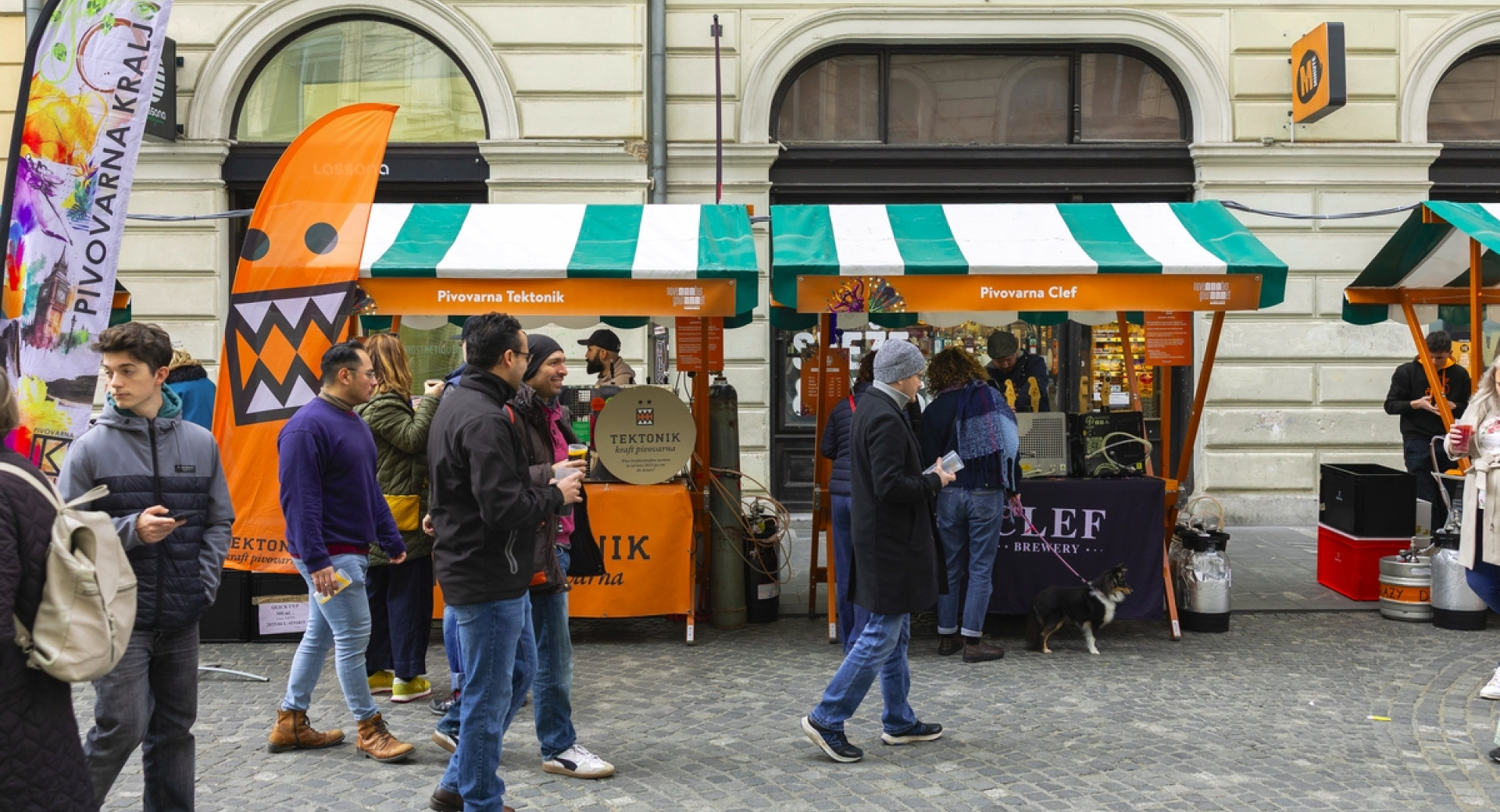 Ljudje na ulici v mestu, kjer so postavljene stojnice.
