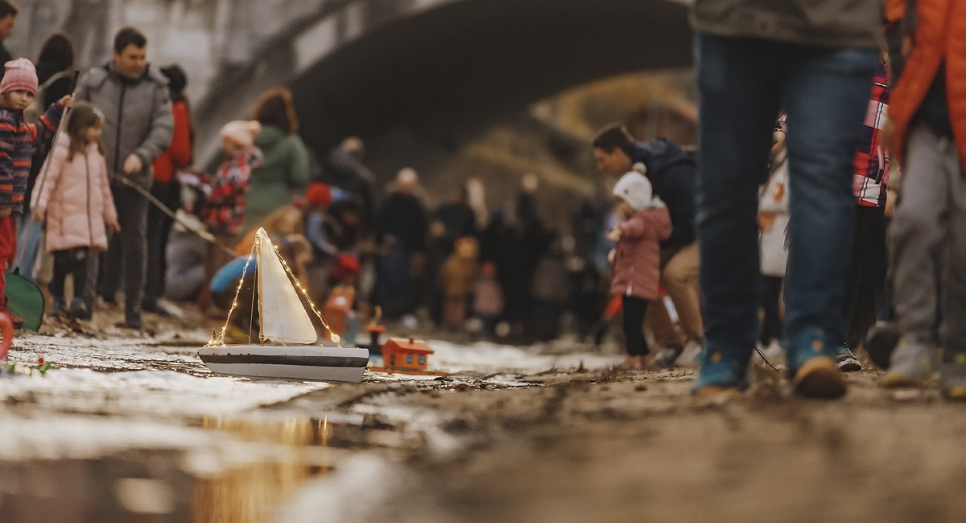 Ladjica na rečici, ob njej ljudje.