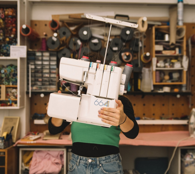A person holding a sewing machine in front of them.