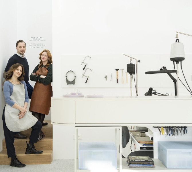 A white table with lights, with three people standing next to it.