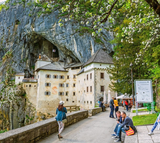 Visitors in front of a castle built into a cliff.