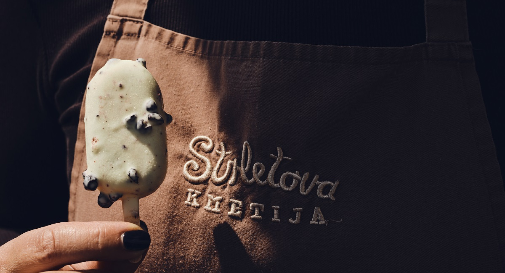 Bela sladoledna lučka z borovnicami pred predpasnikom z oznako "Strletova kmetija".