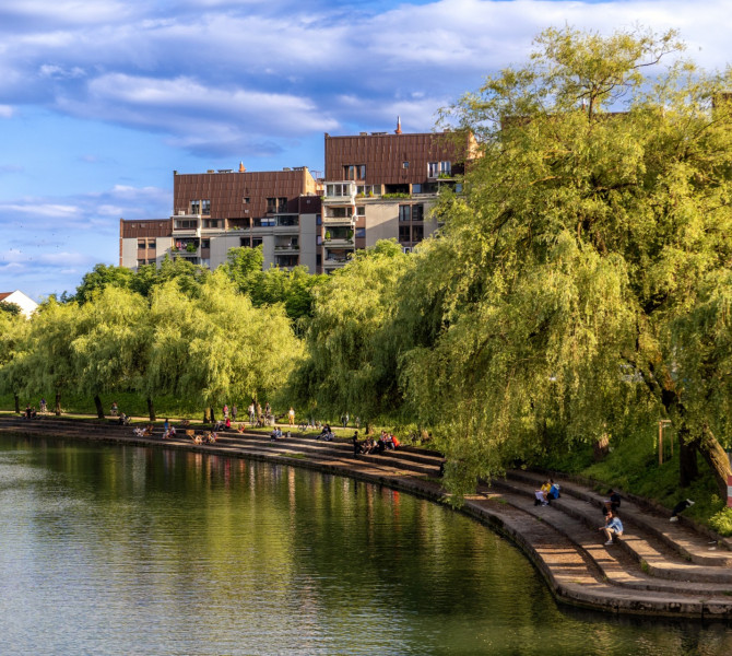 Une rivière traversant la ville, avec une berge verdoyante sur le côté gauche.
