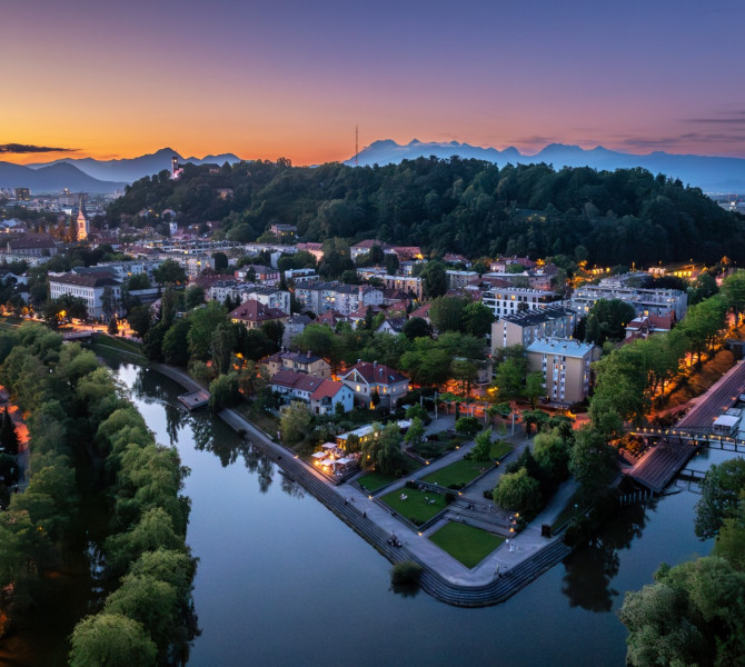 Vecerni pogled na mesto in reke, ki tece skozi, v daljavi grad na hribu.