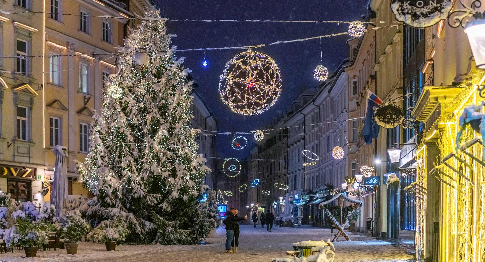 Sapin de Noël et ornements dans la vieille ville enneigée. Un couple devant le sapin