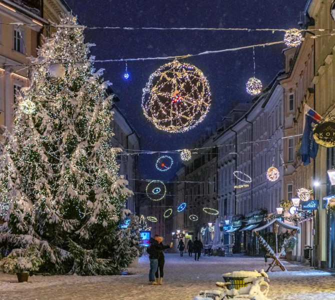 Sapin de Noël et ornements dans la vieille ville enneigée. Un couple devant le sapin