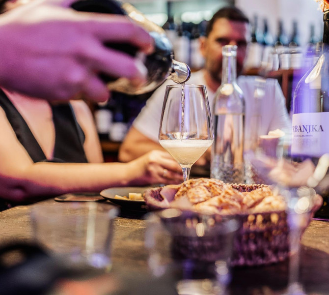 Eine Hand, die eine Flasche hält und Wein in ein Glas einschenkt.