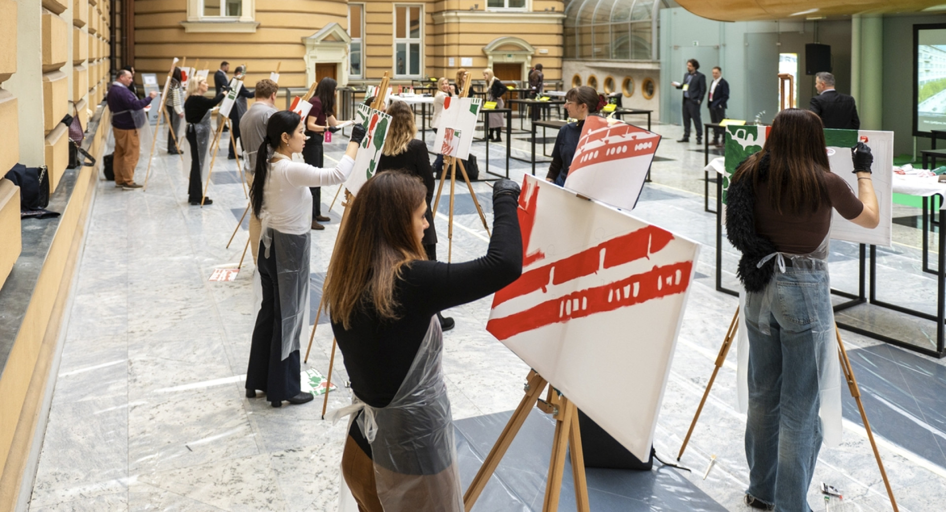 Večje število ljudi ustvarja slike na stojalih.