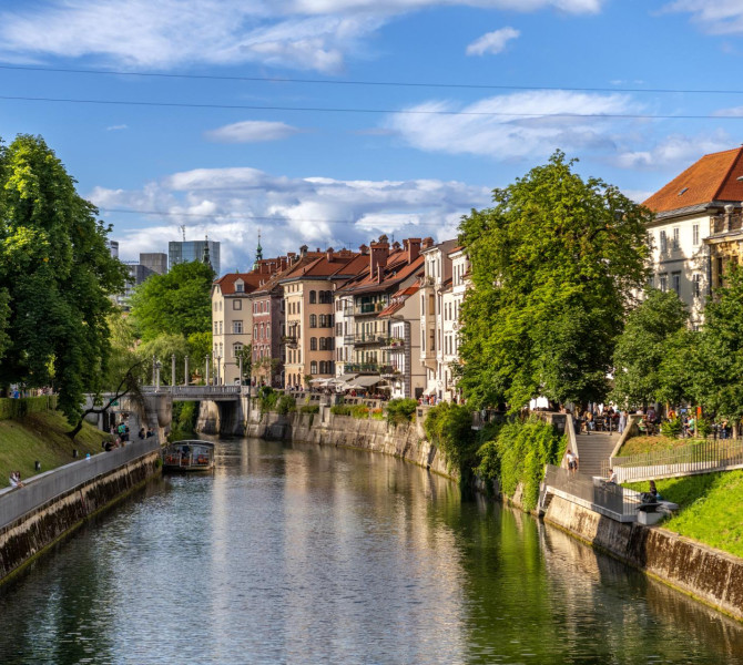 Reka skozi mesto, na levi strani zelenje in na desni strani mescanske hise.
