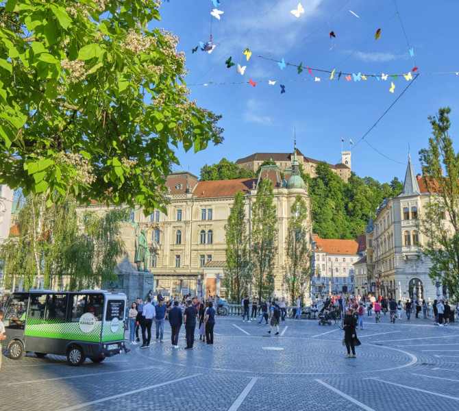 A city square surrounded by buildings, with a castle on the hill.