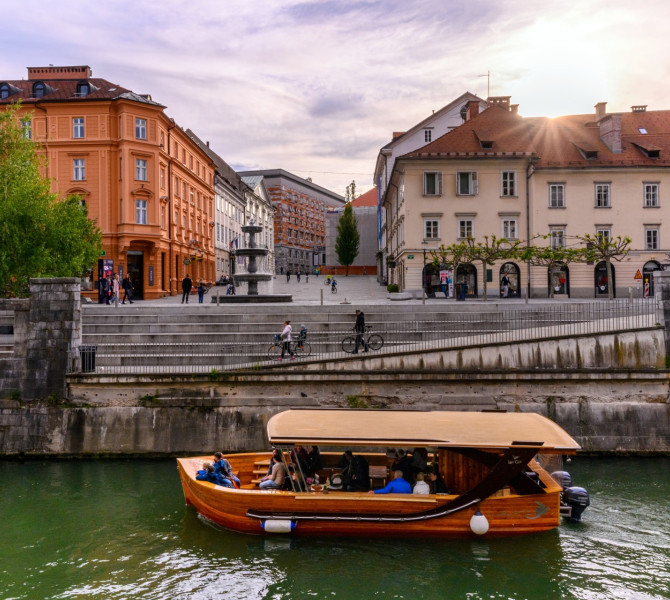 Ein Holzboot auf dem Fluss, im Hintergrund Bürgerhäuser.