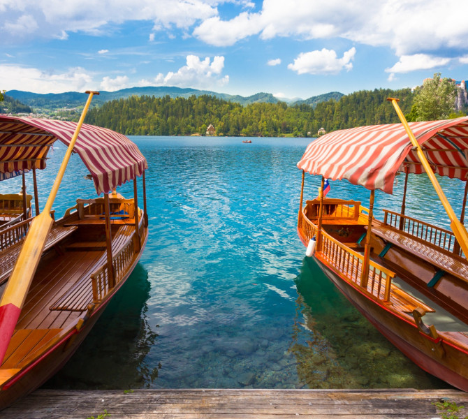 Two wooden boats with a large oar and a covered roof on the lake.
