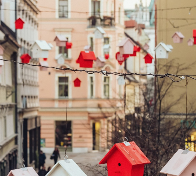 Razobešene ptičje hišice v različnih barvah nad ulico v mestu. 