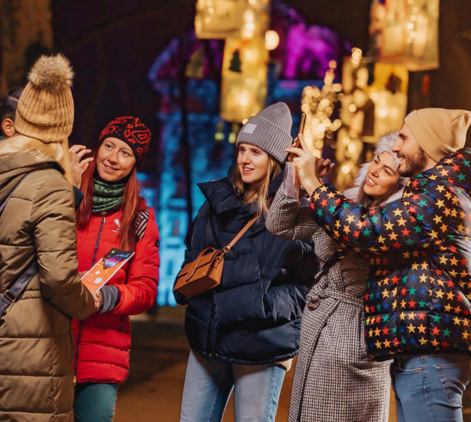 Un couple au sein d'un groupe se prend en photo sous les lumières festives.
