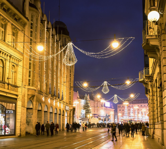 Una strada in città decorata con luci natalizie, illuminata di giallo.