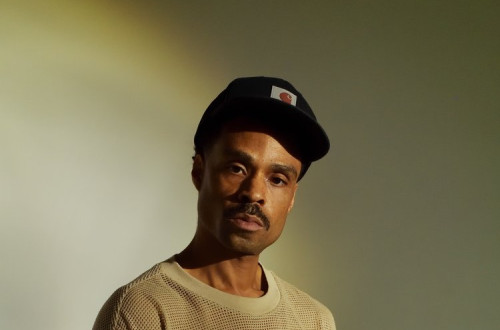 Temnopolt moski s crno cepico in belim puloverjem.