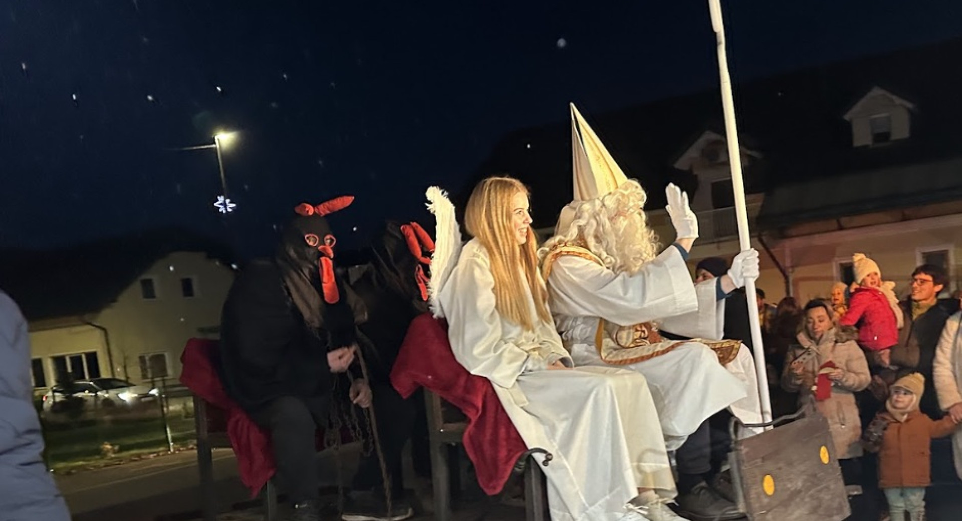 V kociji se cez mesto peljejo Miklavz, angel in parkeljni.