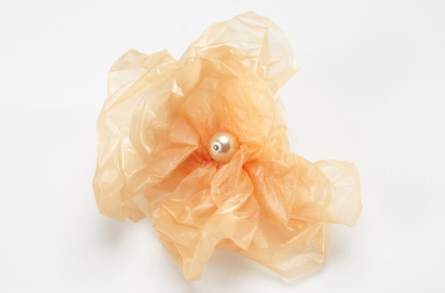 Fotografija bisera v oranzni zmeckani plastiki na belem ozadju.