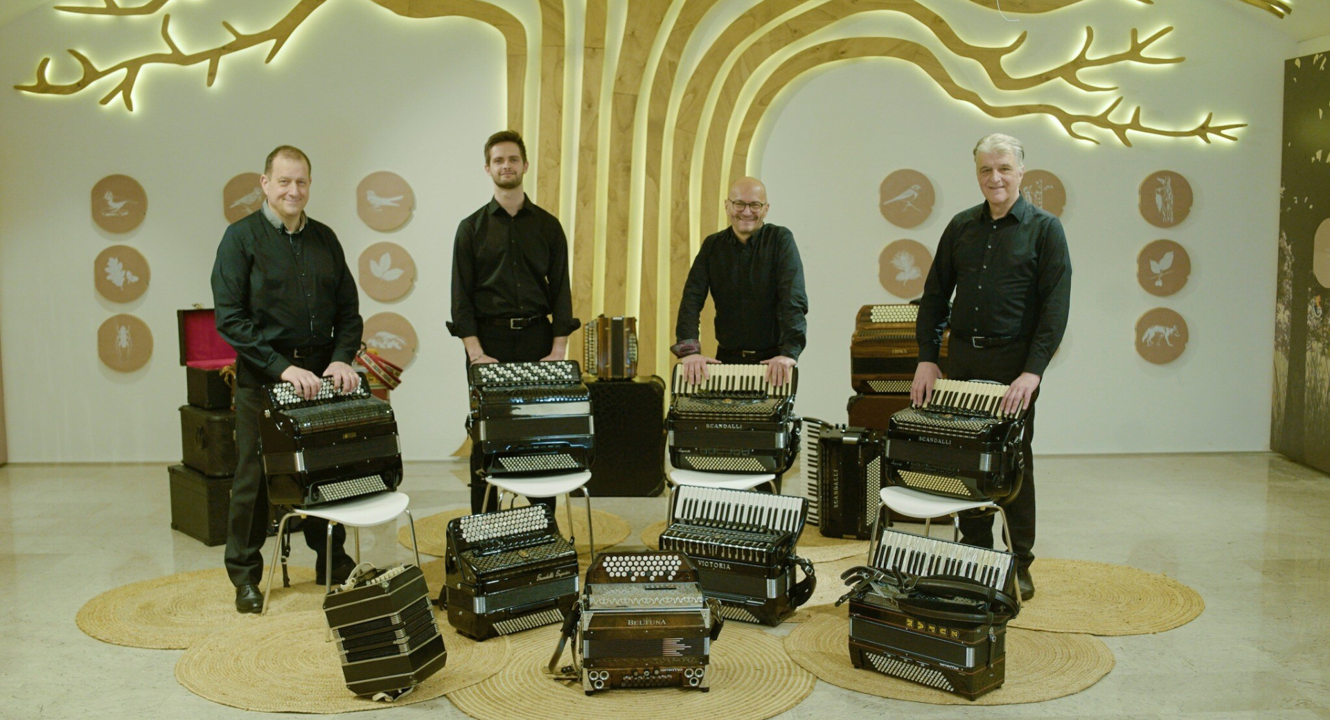 Stirje glasbeniki s hramonikami v sobi.