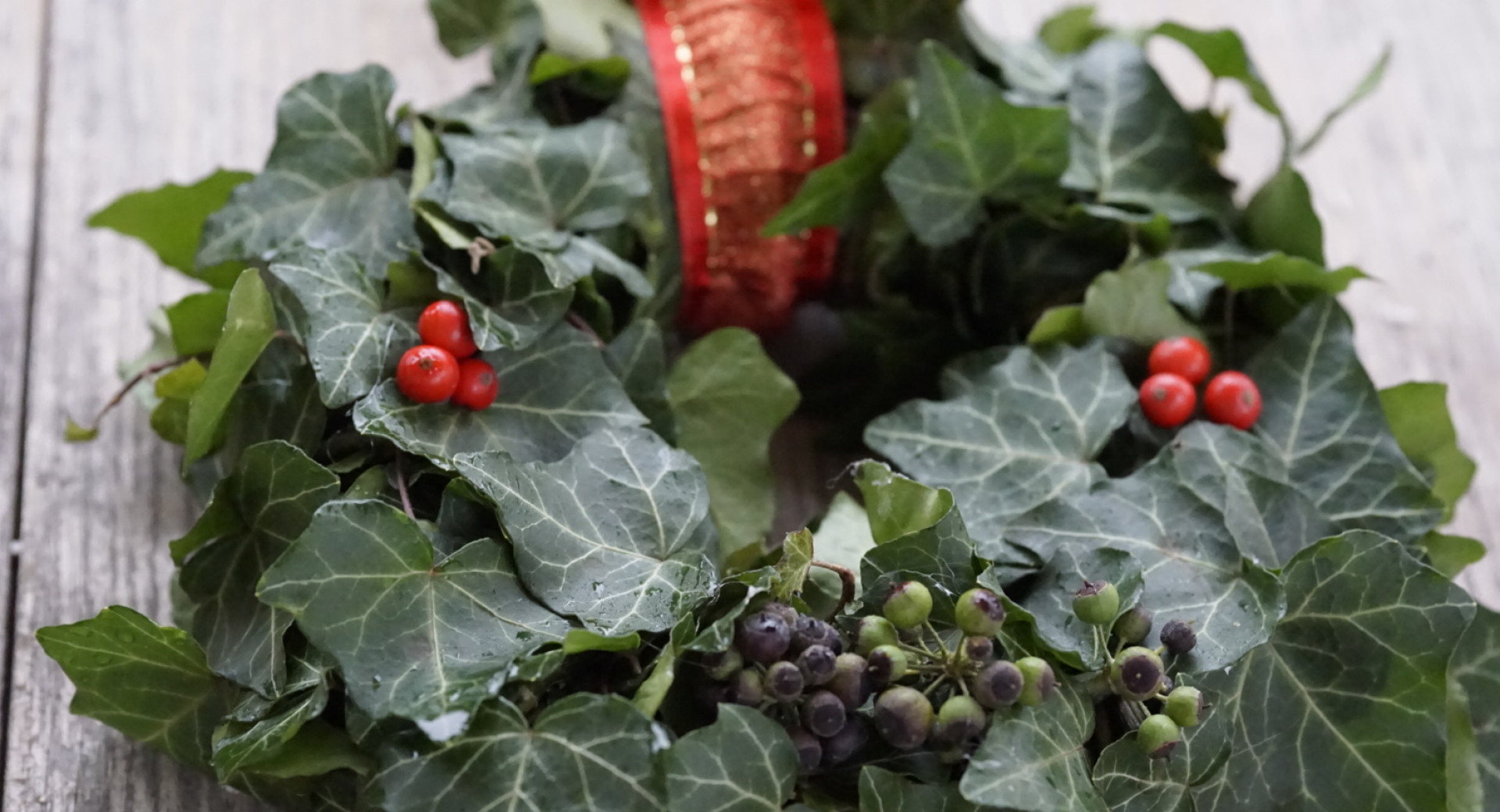 Rocno narejen adventni vencek na sivi leseni mizi.