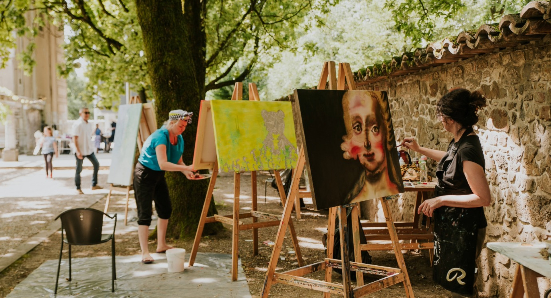 Slikarji slikajo na platna med drevesi.