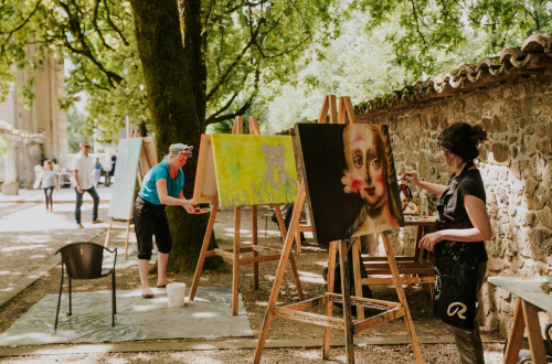 Slikarji slikajo na platna med drevesi.