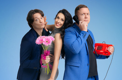 Dva moska in ena zenska pozirajo za fotografijo na modrem ozadju; eden drzi v roki roznat sopek, drugi pa rdec zicni telefon, zenska je med njima z valjarjem v roki.