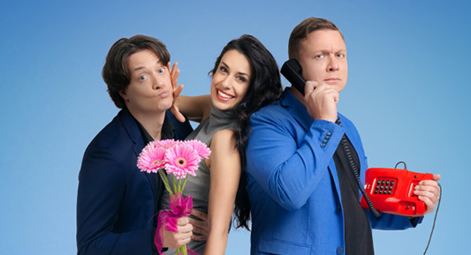 Dva moska in ena zenska pozirajo za fotografijo na modrem ozadju; eden drzi v roki roznat sopek, drugi pa rdec zicni telefon, zenska je med njima z valjarjem v roki.