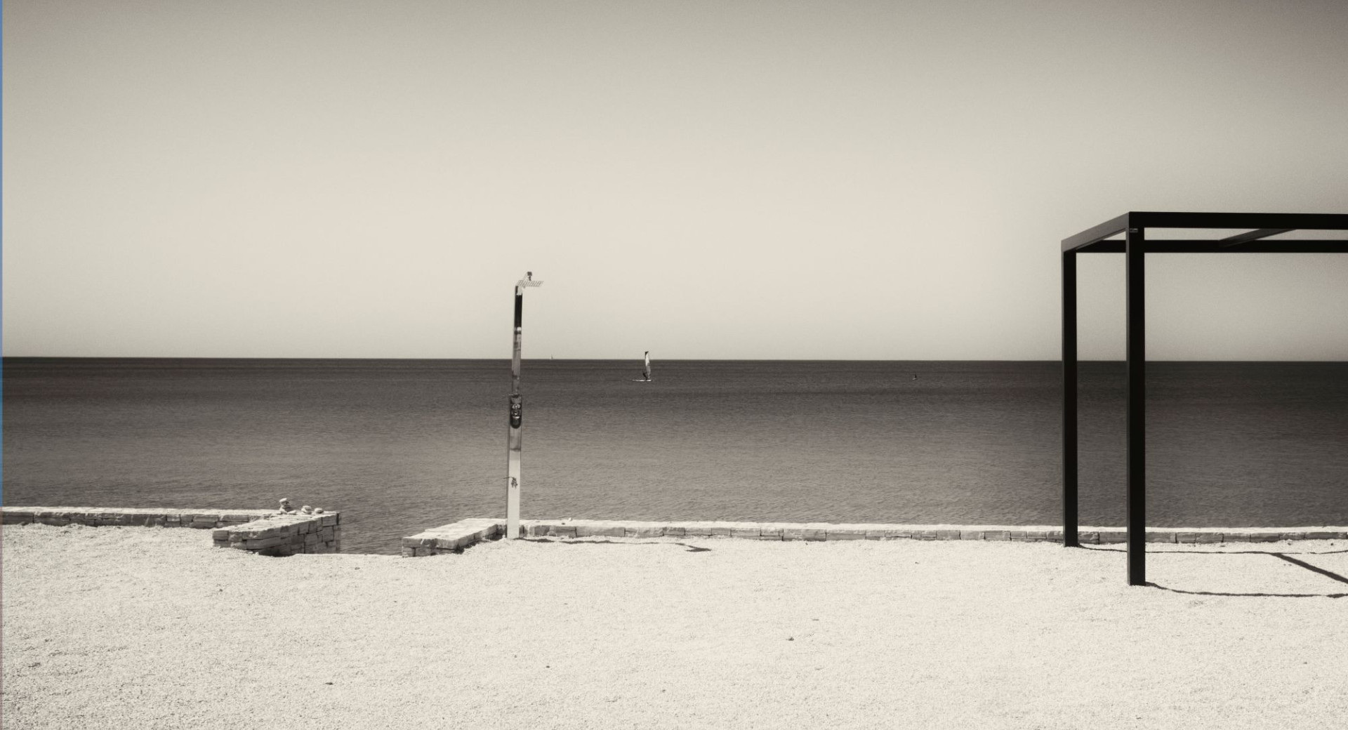 Coastal landscape, photographed from a stone beach, in black and white.