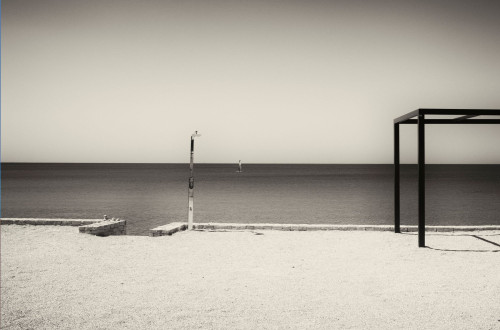Coastal landscape, photographed from a stone beach, in black and white.