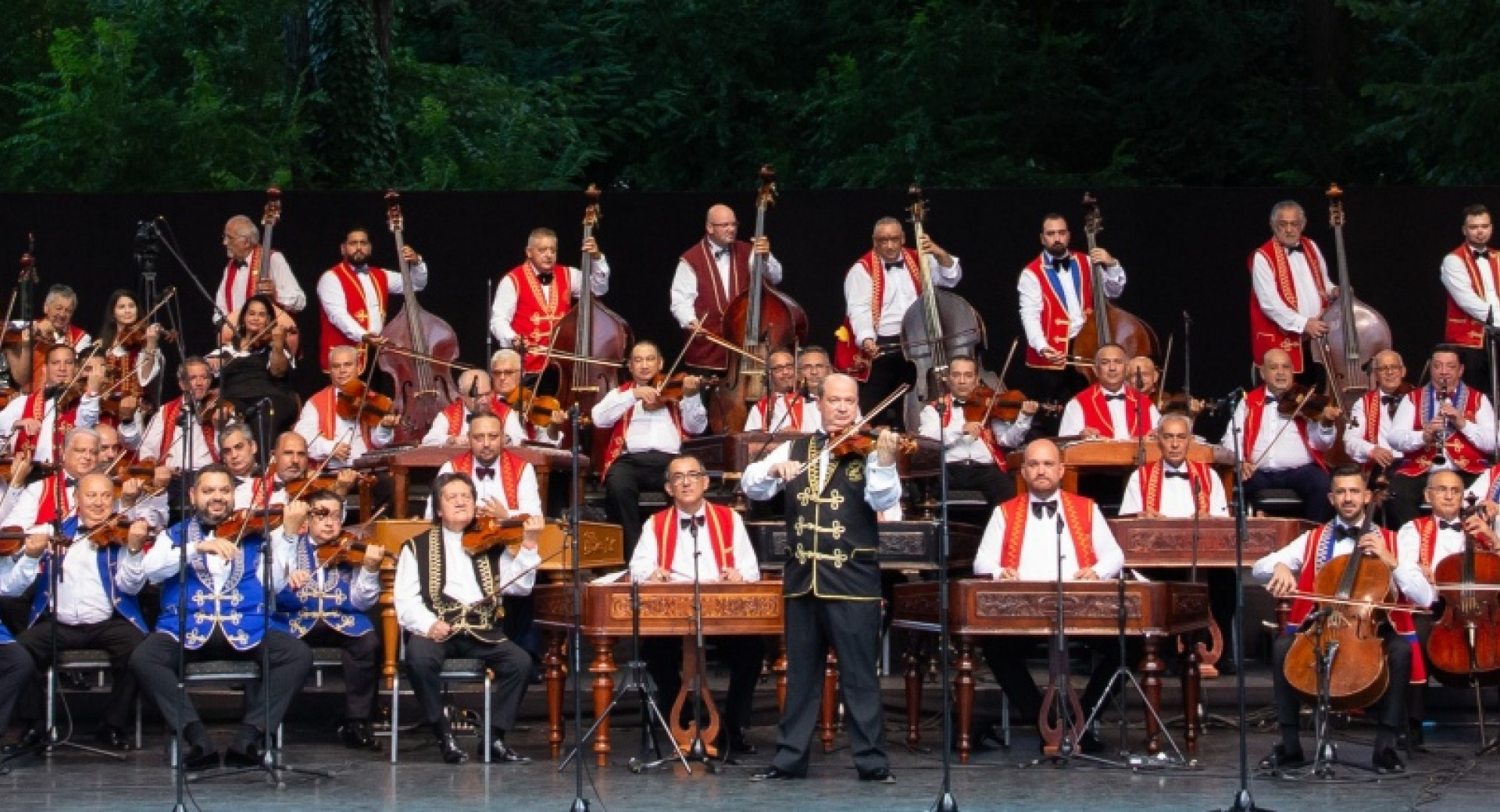 The orchestra on stage in white shirts and blue and red jackets.