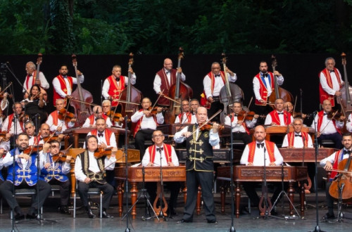 Orkester na odru v belih srajcah in modrih ter rdecih suknjicih.