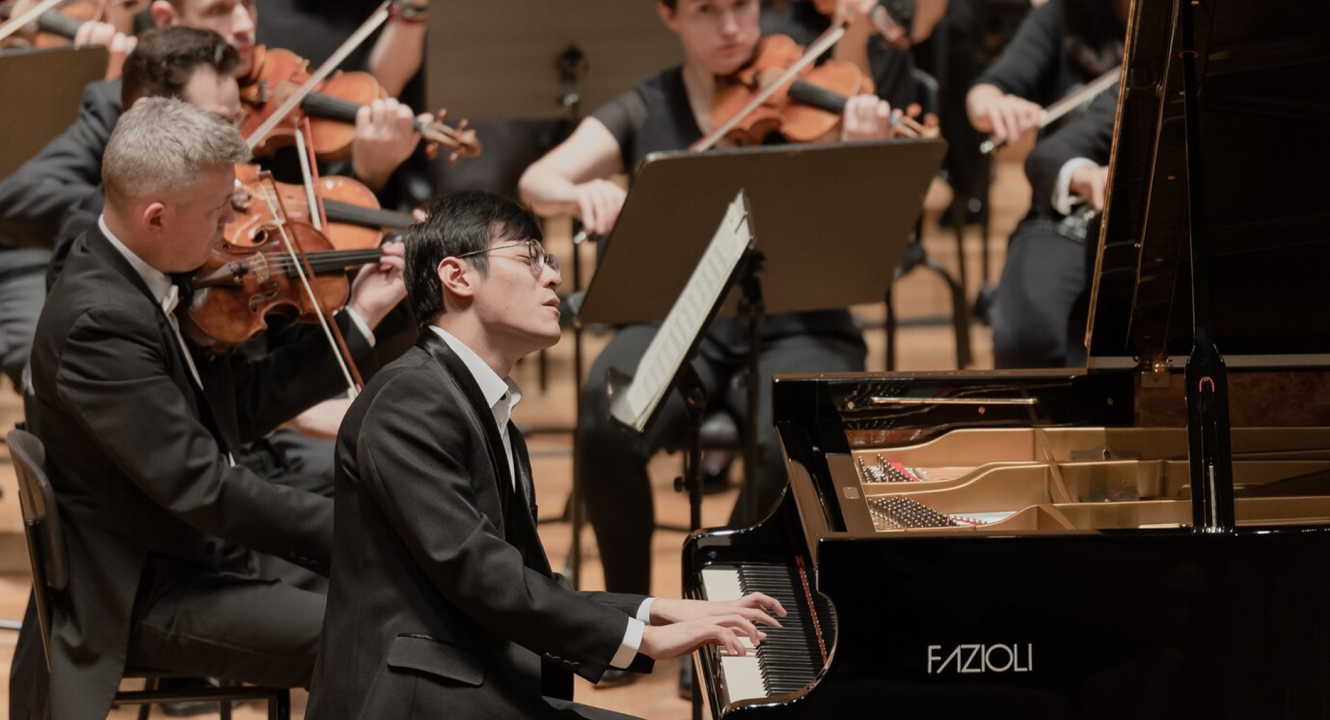 Moski igra na klavir, za njim pa cel orkester.