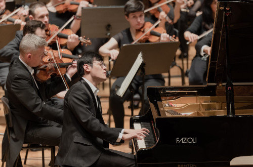 Moski igra na klavir, za njim pa cel orkester.