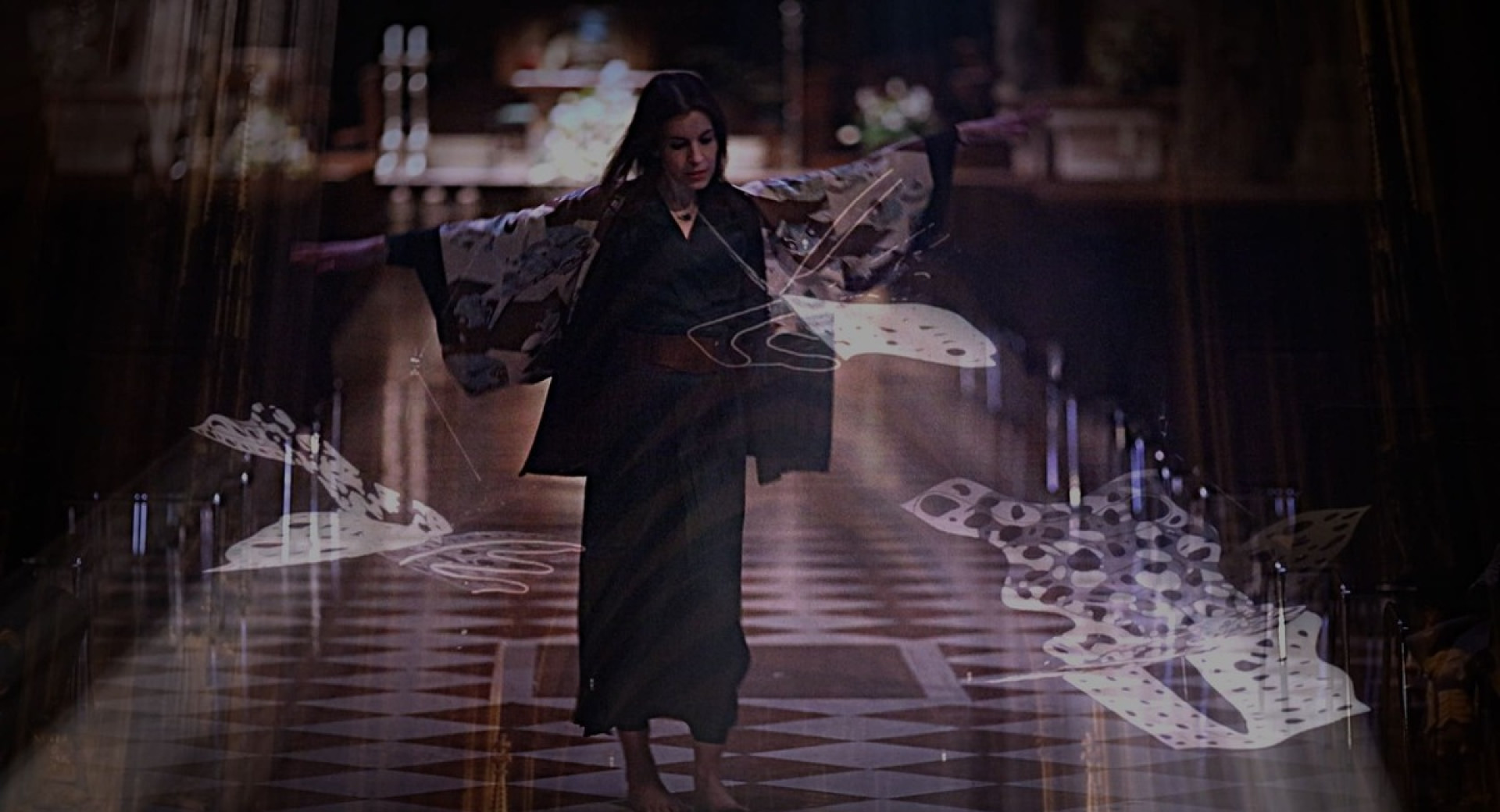 A woman in a dark kimono walks through a church, surrounded by light installations.