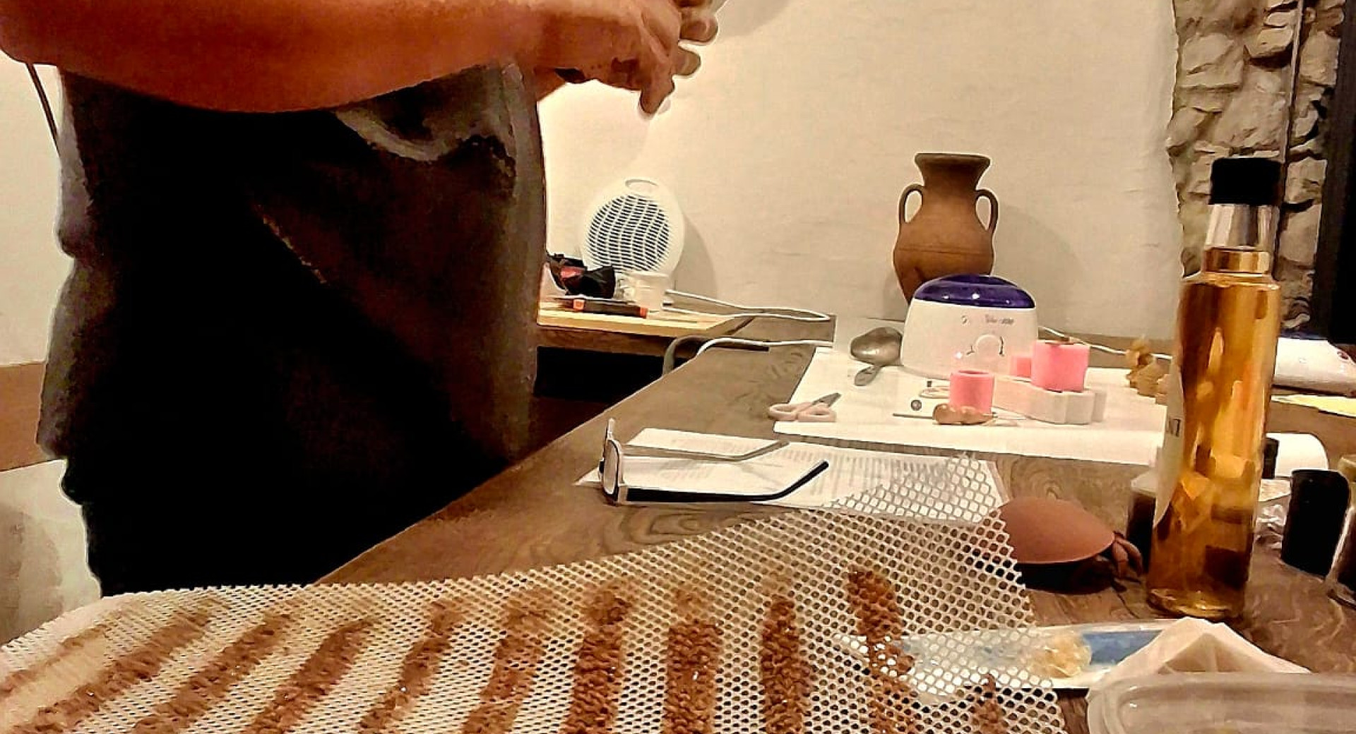 Moski je na levi za mizo, na kateri je vse potrebno za izdelavo svec.