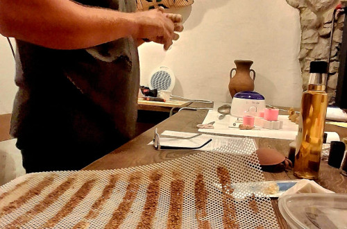 Moski je na levi za mizo, na kateri je vse potrebno za izdelavo svec.