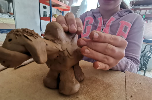 Bliznji posnetek rok dekleta, ki izdeluje kipec iz gline.