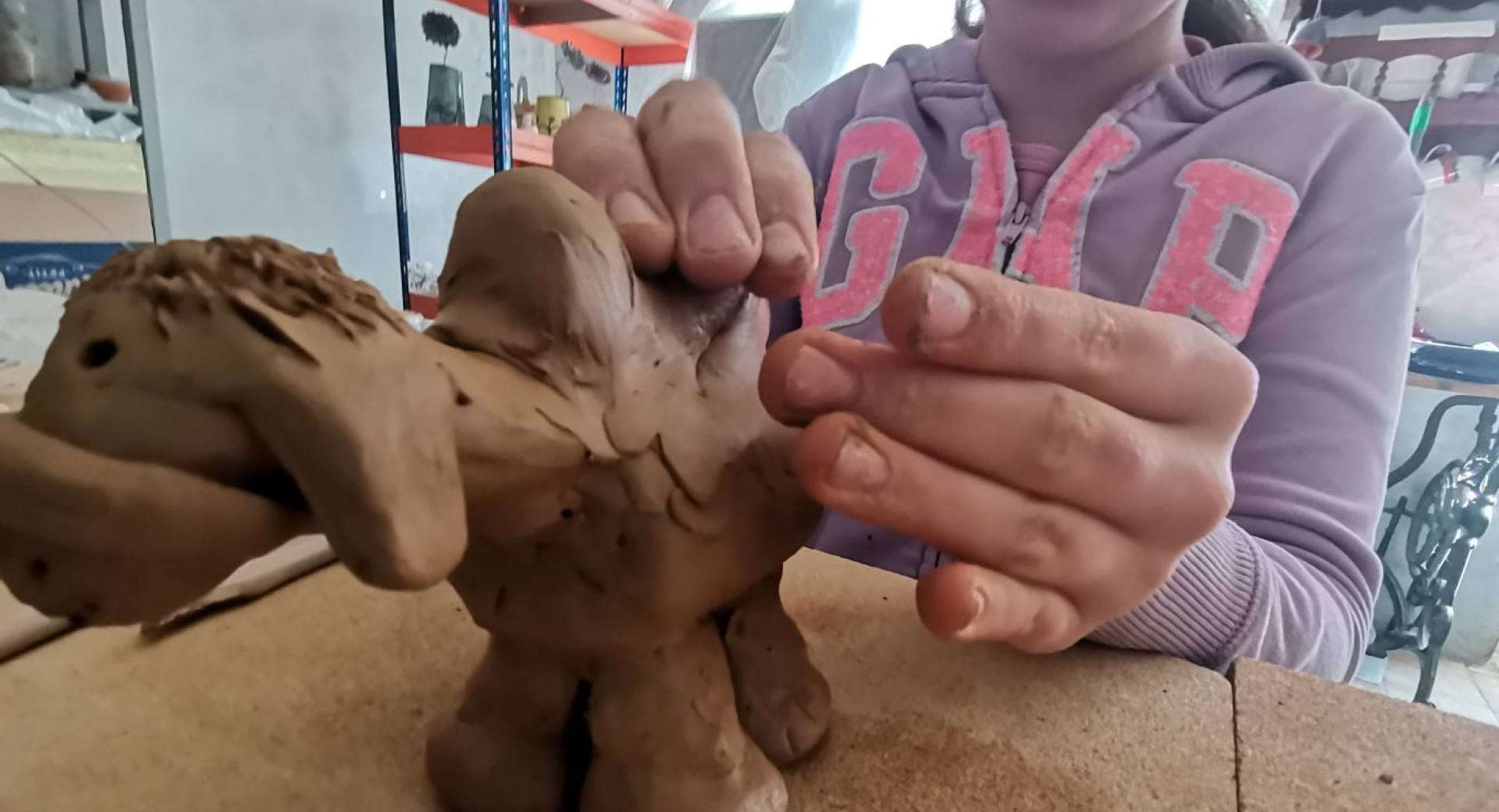 Bliznji posnetek rok dekleta, ki izdeluje kipec iz gline.