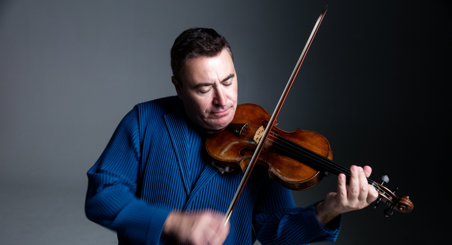 Moski v modri obleki igra na violino.