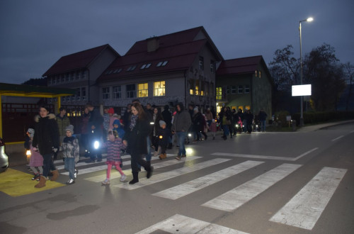 Ljudje se skupaj sprehajajo po cesti in v rokah drzijo lucke.