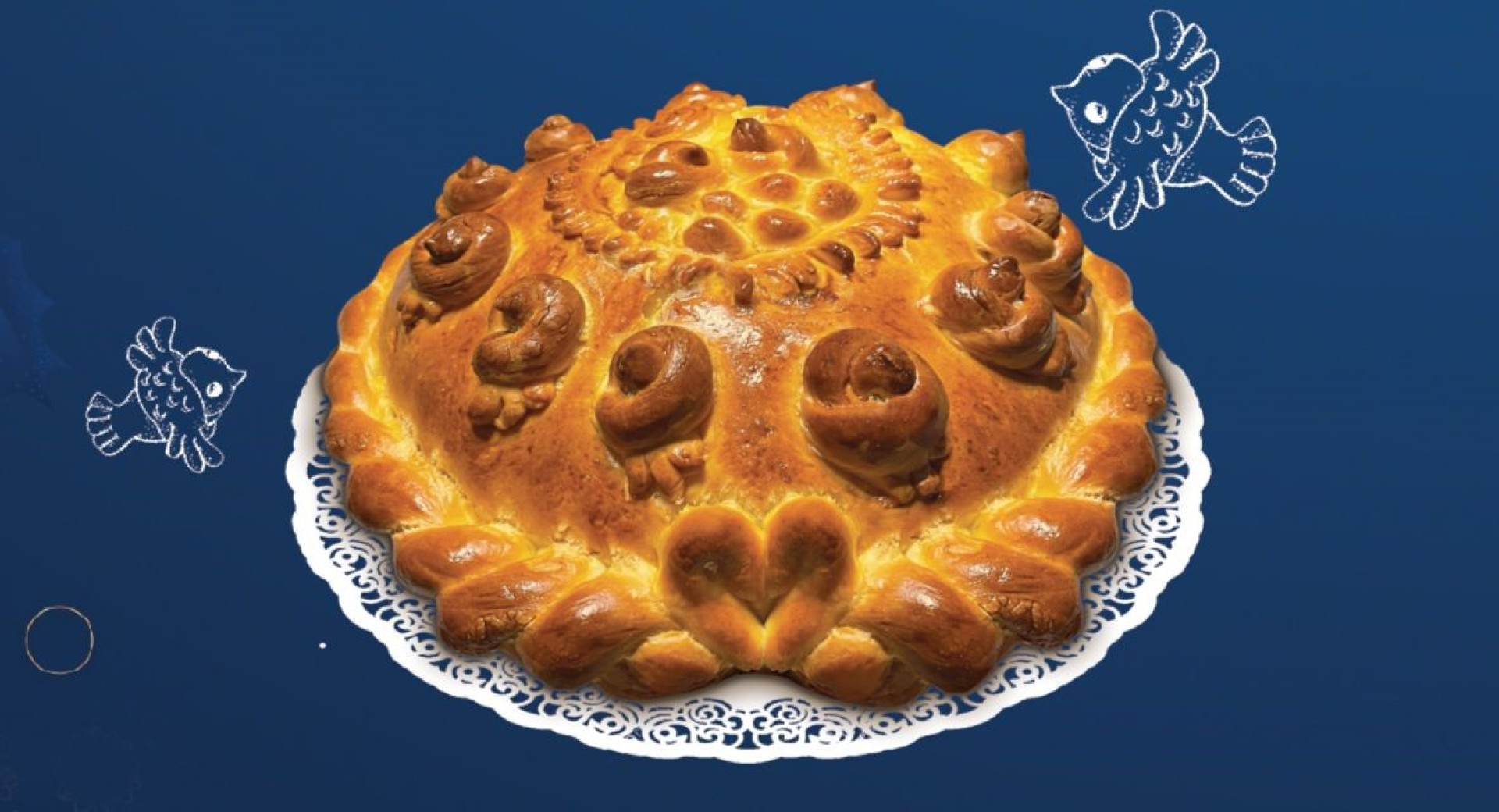 Bozicni kruh na belem prticu, ki je polozen na temno modrem prtu.