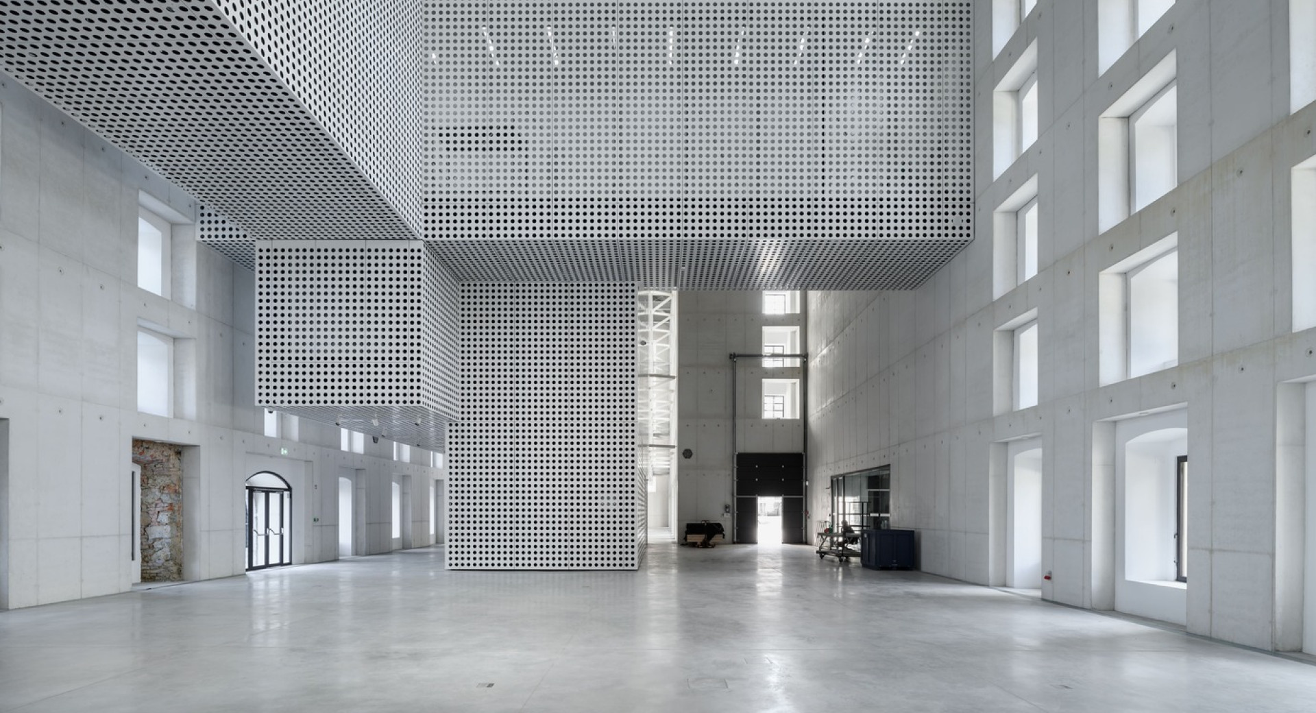 Notranjost velike hale, kjer je vse v beli barvi, z velikimi okni, ki osvetljujejo prostor z naravno svetlobo.