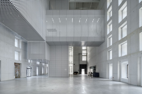 Notranjost velike hale, kjer je vse v beli barvi, z velikimi okni, ki osvetljujejo prostor z naravno svetlobo.