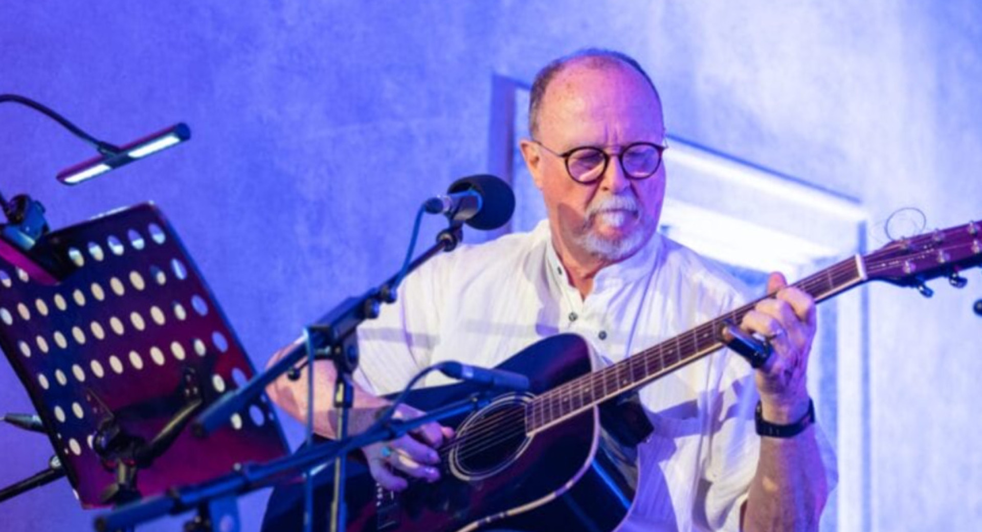 The performer on stage is playing the guitar.
