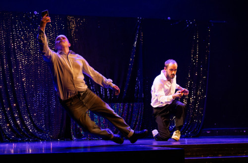 Two men on stage during a dance performance. 