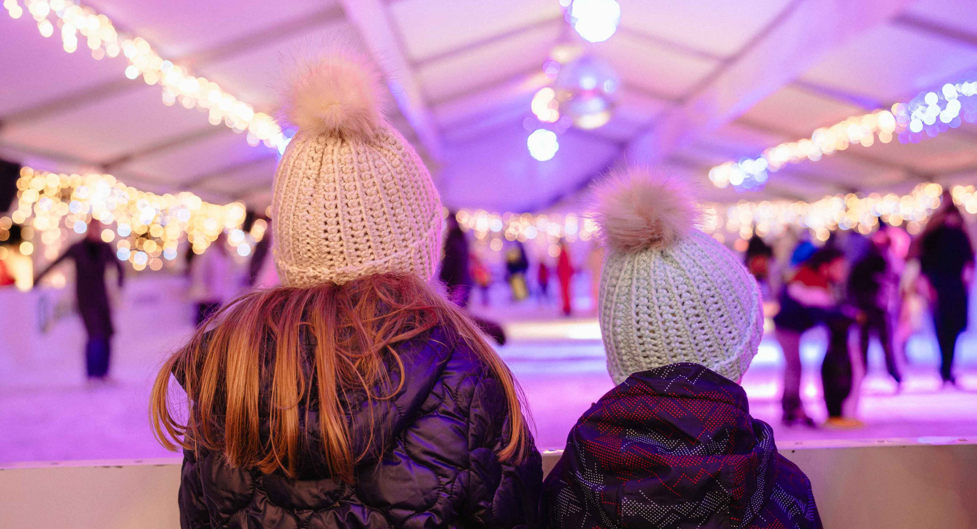 Punca in fant s kapama na glavi sta s hrbtom obrnjena proti kameri in gledata proti drsaliscu, ki je v ozadju fotografije.